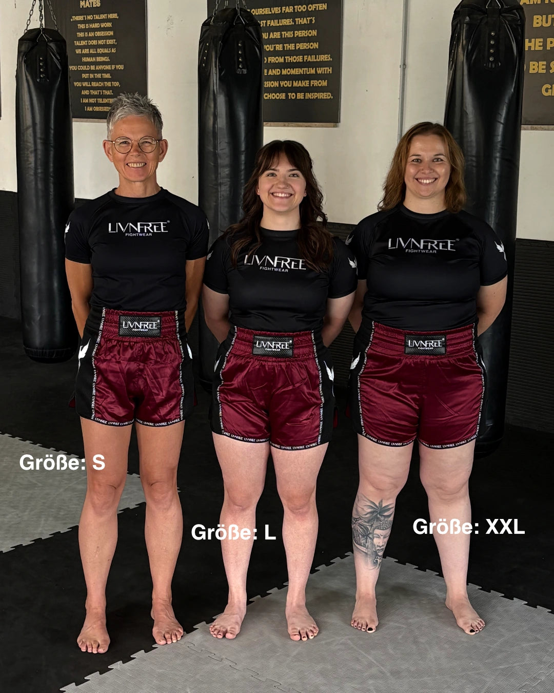 Drei Frauen mit unterschiedlichen Körperformen tragen die 2-in-1 Muay Thai Shorts in Burgund